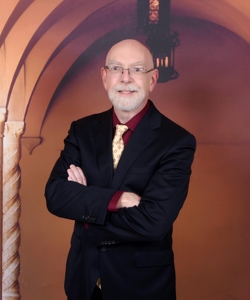 Russell Walker standing with arms folded in a hallway